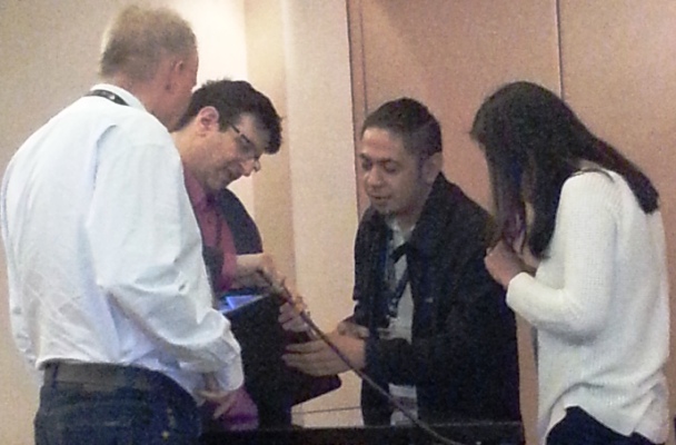 Nils Mulvad, Paul Myers, hotel-tekniker og Irene Jay Liu kæmper for at tilslutte Pauls PC til projektoren. Foto: Matikas Santos.